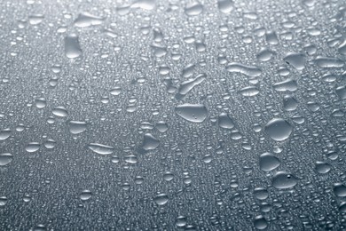 Water drops on grey glass surface, closeup