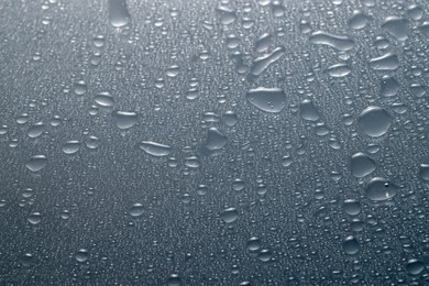 Photo of Water drops on grey glass surface, top view