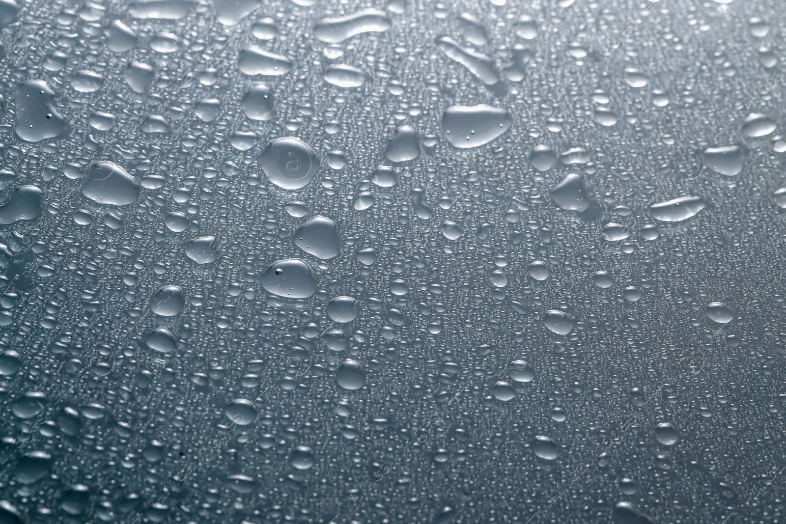 Photo of Water drops on light glass surface, top view