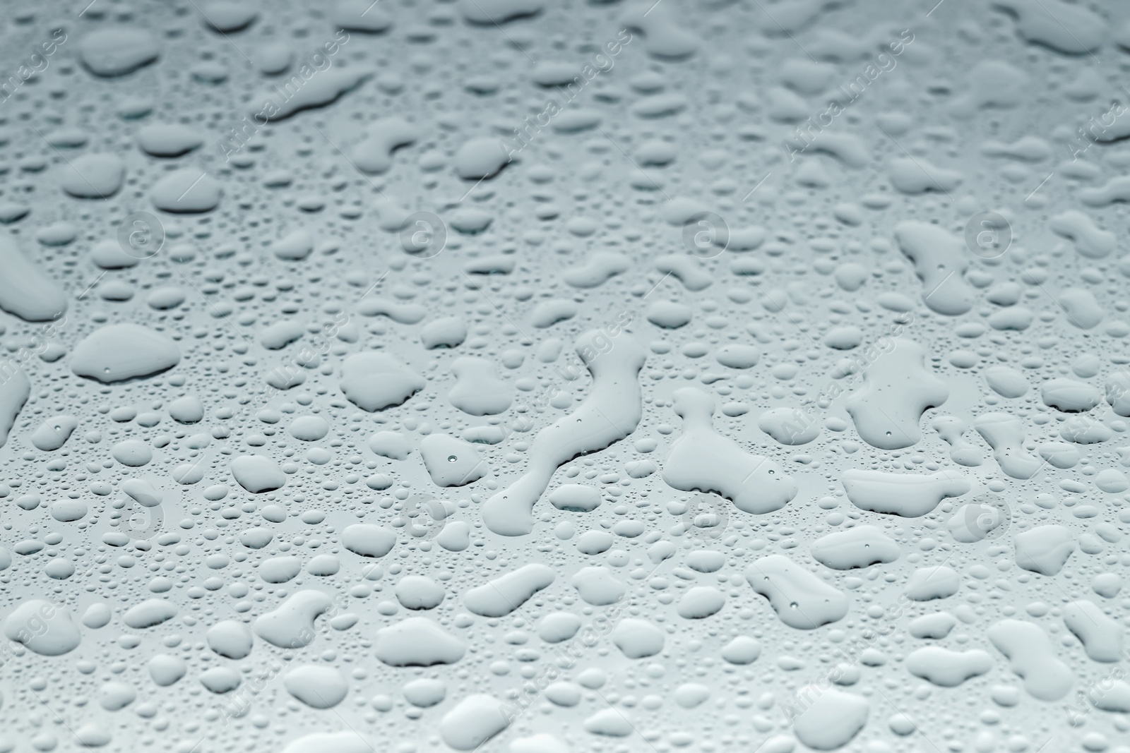 Photo of Water drops on light glass surface, closeup