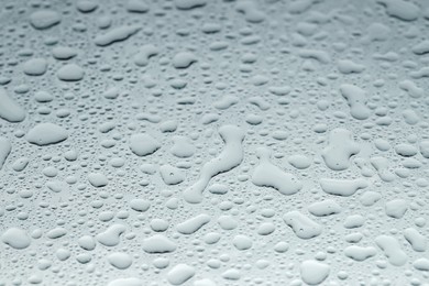 Photo of Water drops on light glass surface, closeup