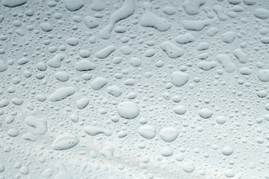 Photo of Water drops on light glass surface, closeup