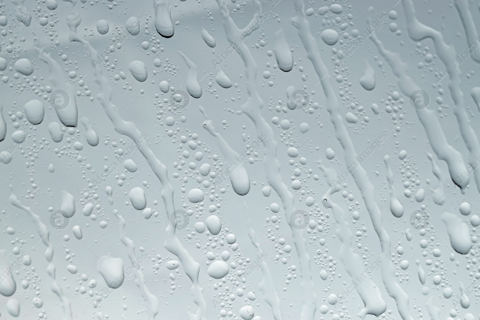 Photo of Water drops on grey glass surface, closeup