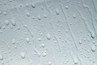 Photo of Water drops on grey glass surface, closeup