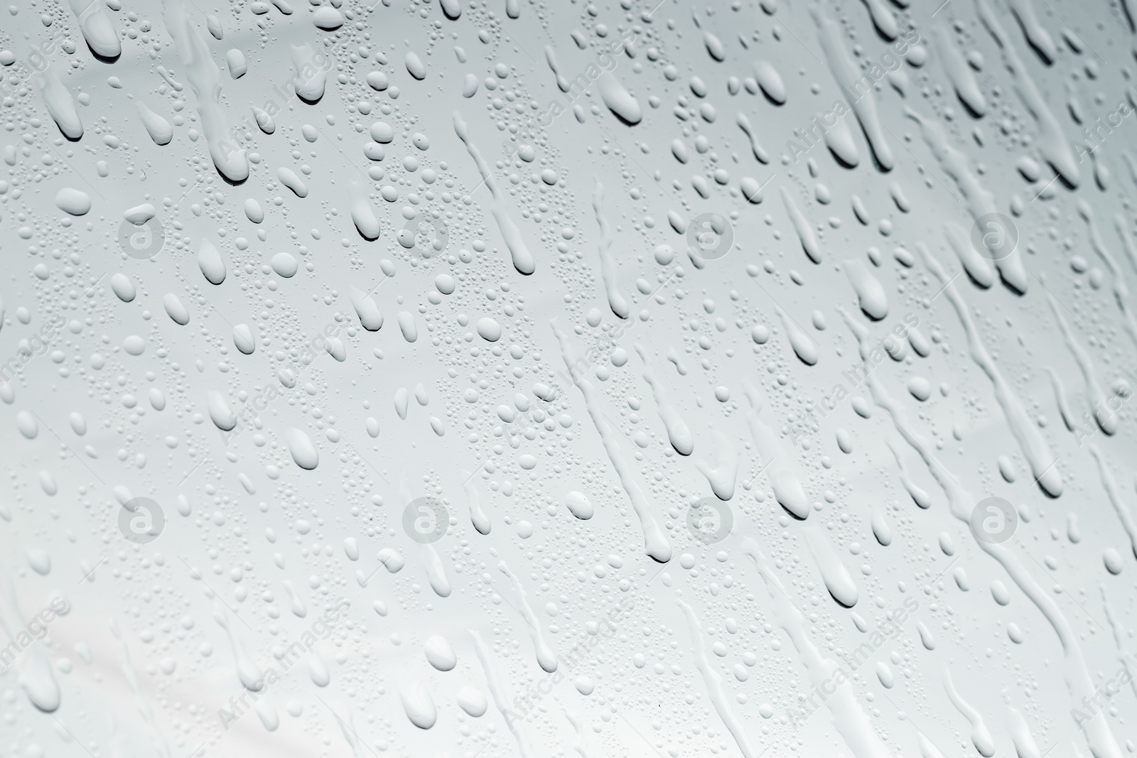 Photo of Water drops on light glass surface, top view