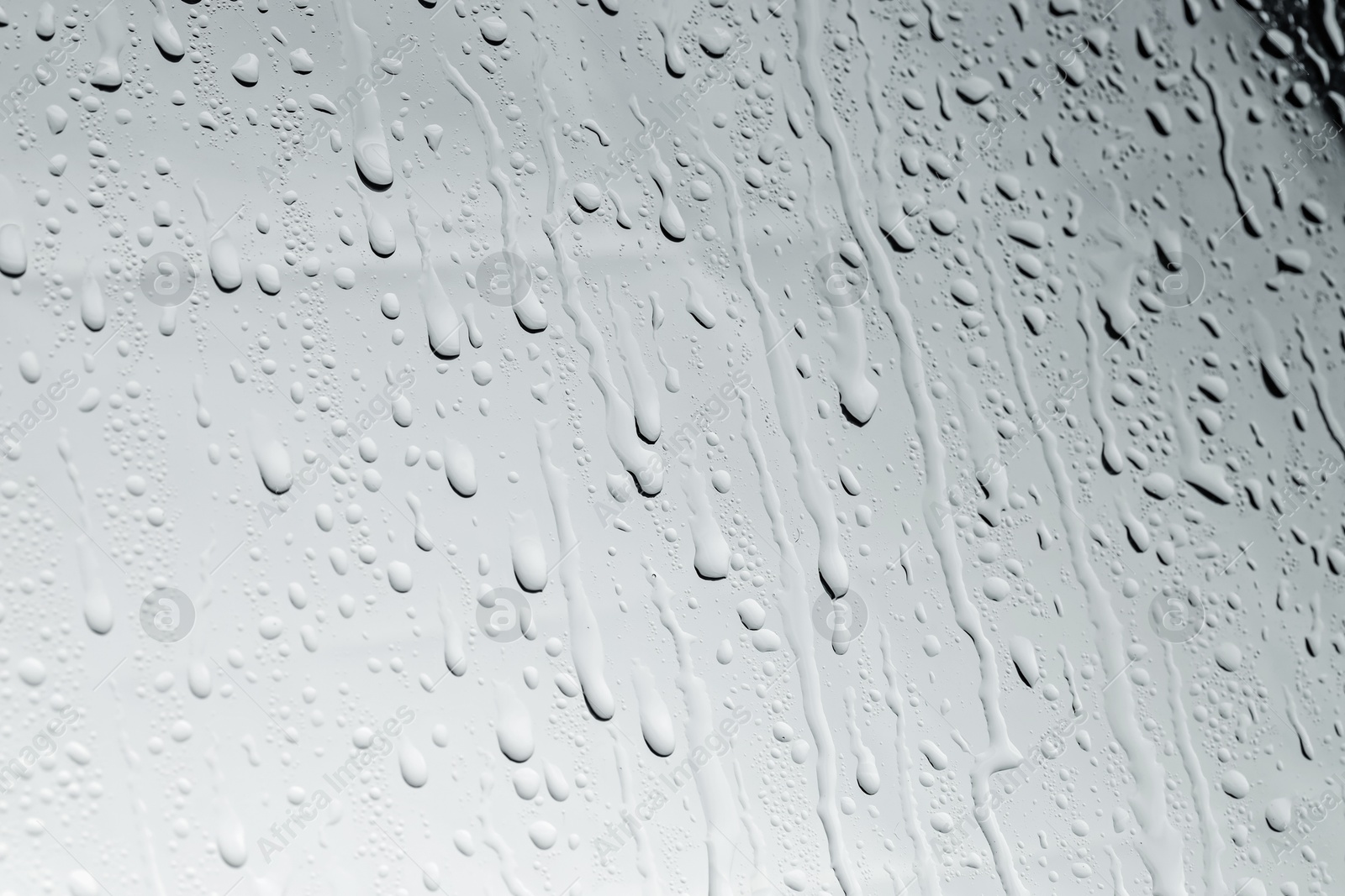 Photo of Water drops on light glass surface, closeup