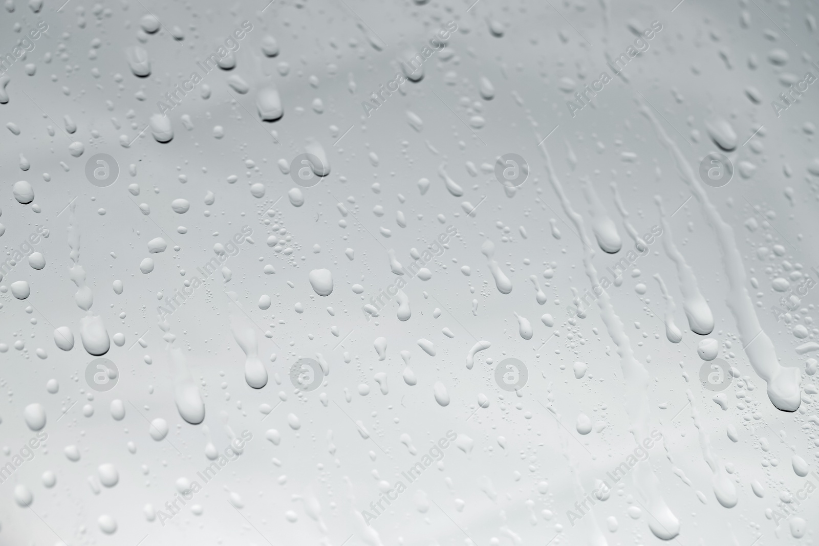 Photo of Water drops on light glass surface, closeup