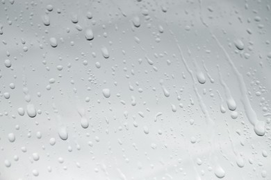 Photo of Water drops on light glass surface, closeup