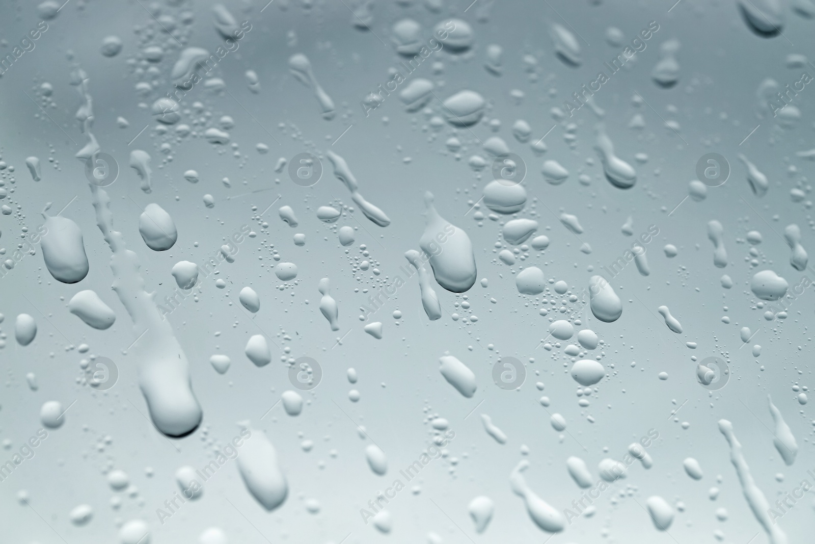 Photo of Water drops on light glass surface, closeup