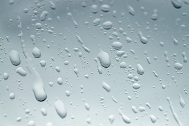 Water drops on light glass surface, closeup