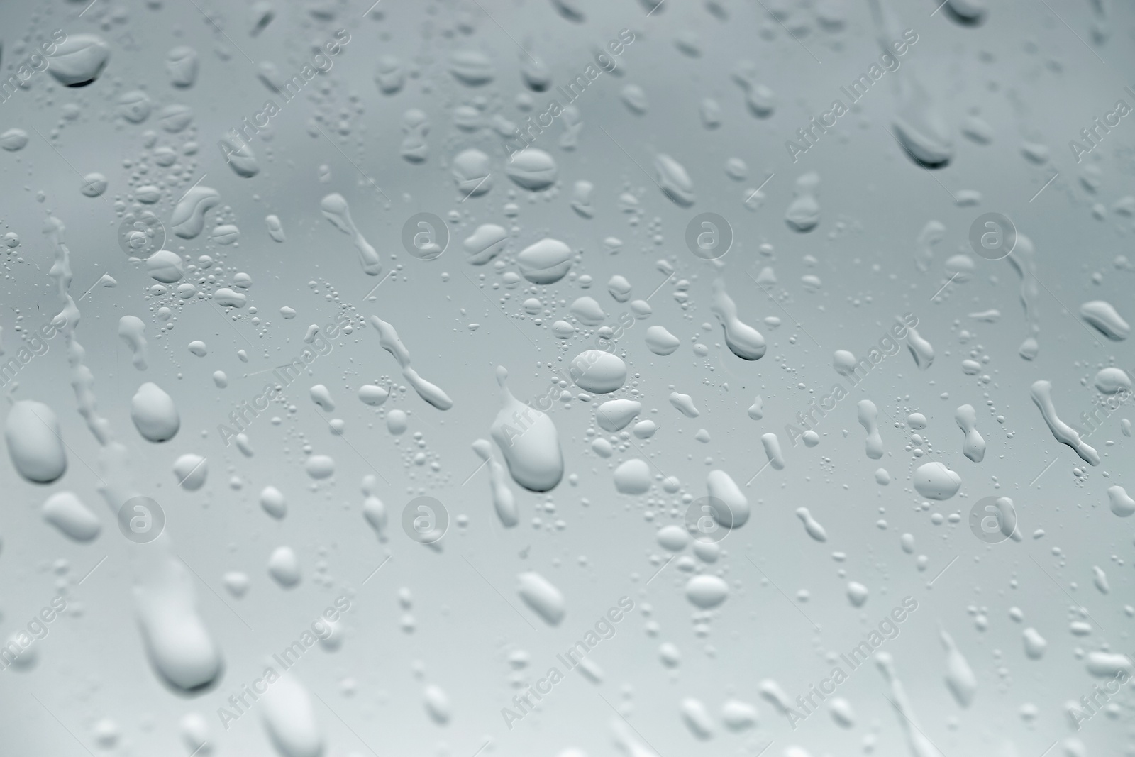 Photo of Water drops on light glass surface, closeup