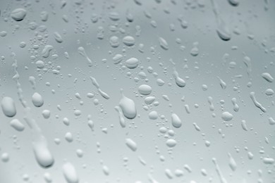 Photo of Water drops on light glass surface, closeup