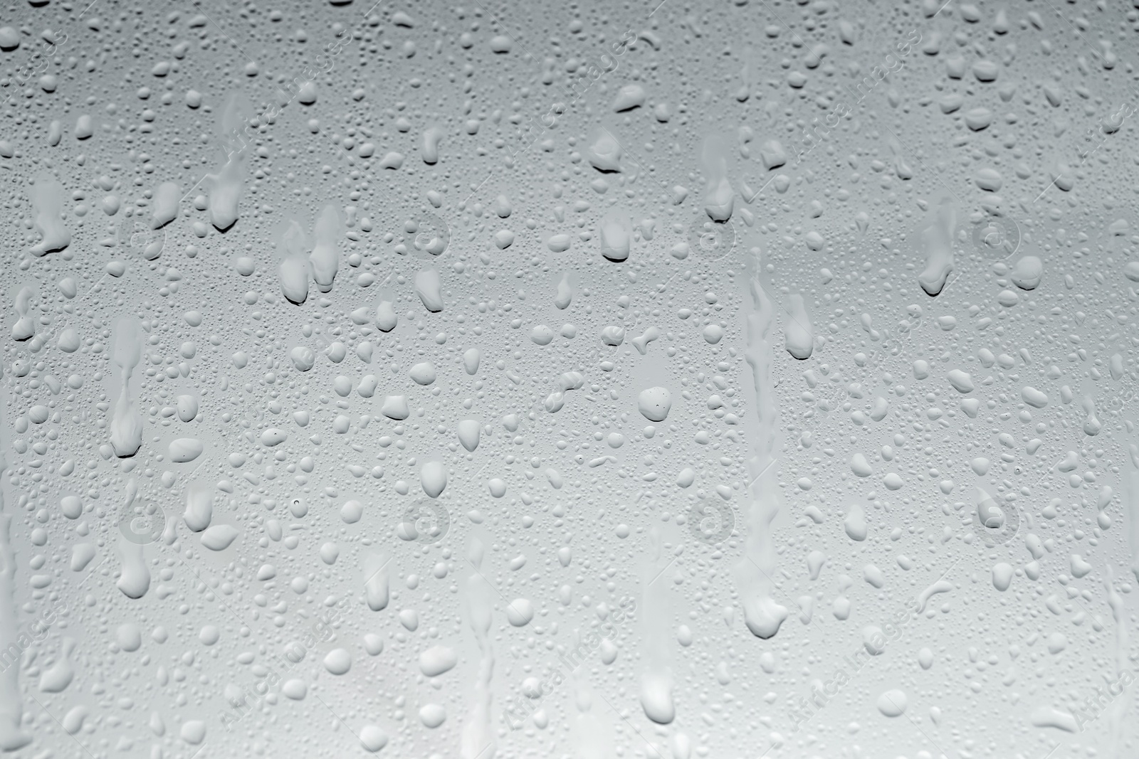 Photo of Water drops on light glass surface, top view