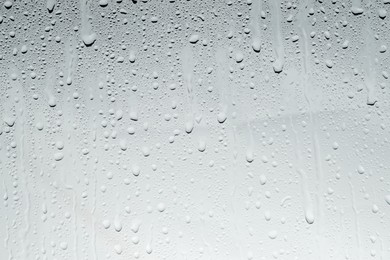 Photo of Water drops on light glass surface, top view