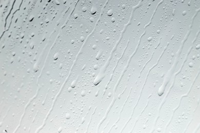 Photo of Water drops on light glass surface, top view