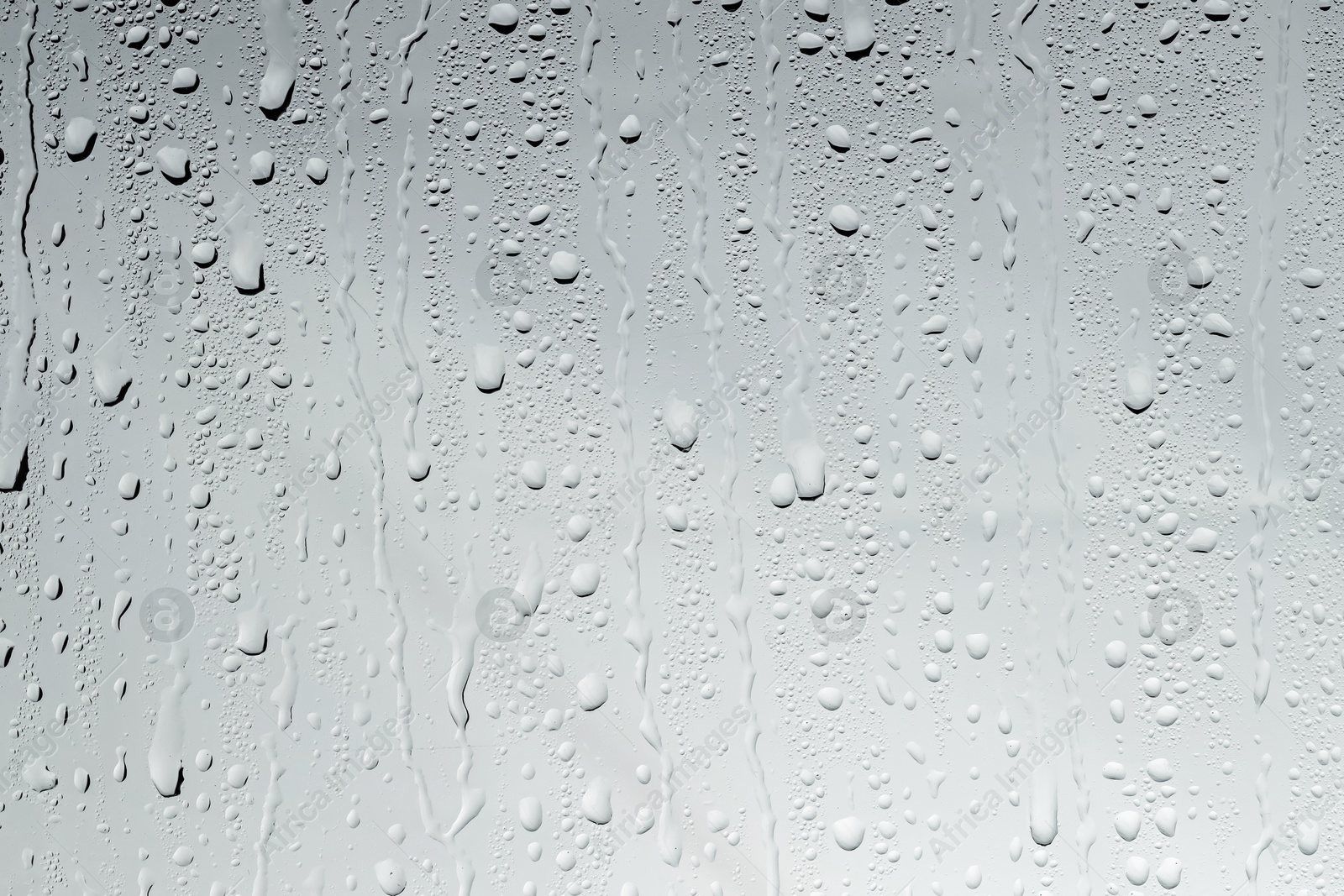 Photo of Water drops on light glass surface, top view