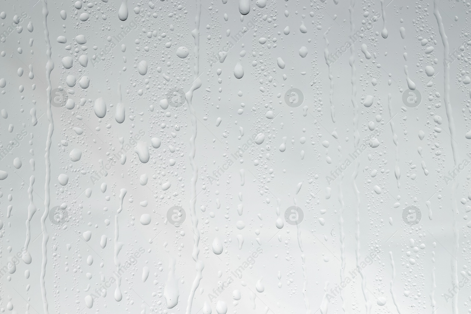 Photo of Water drops on light glass surface, top view