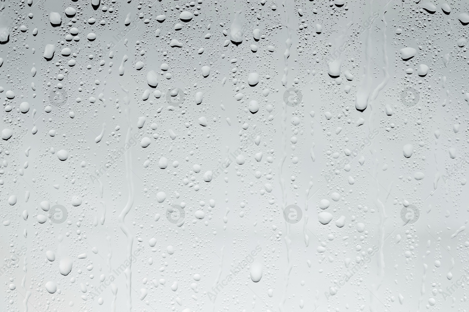 Photo of Water drops on light glass surface, top view