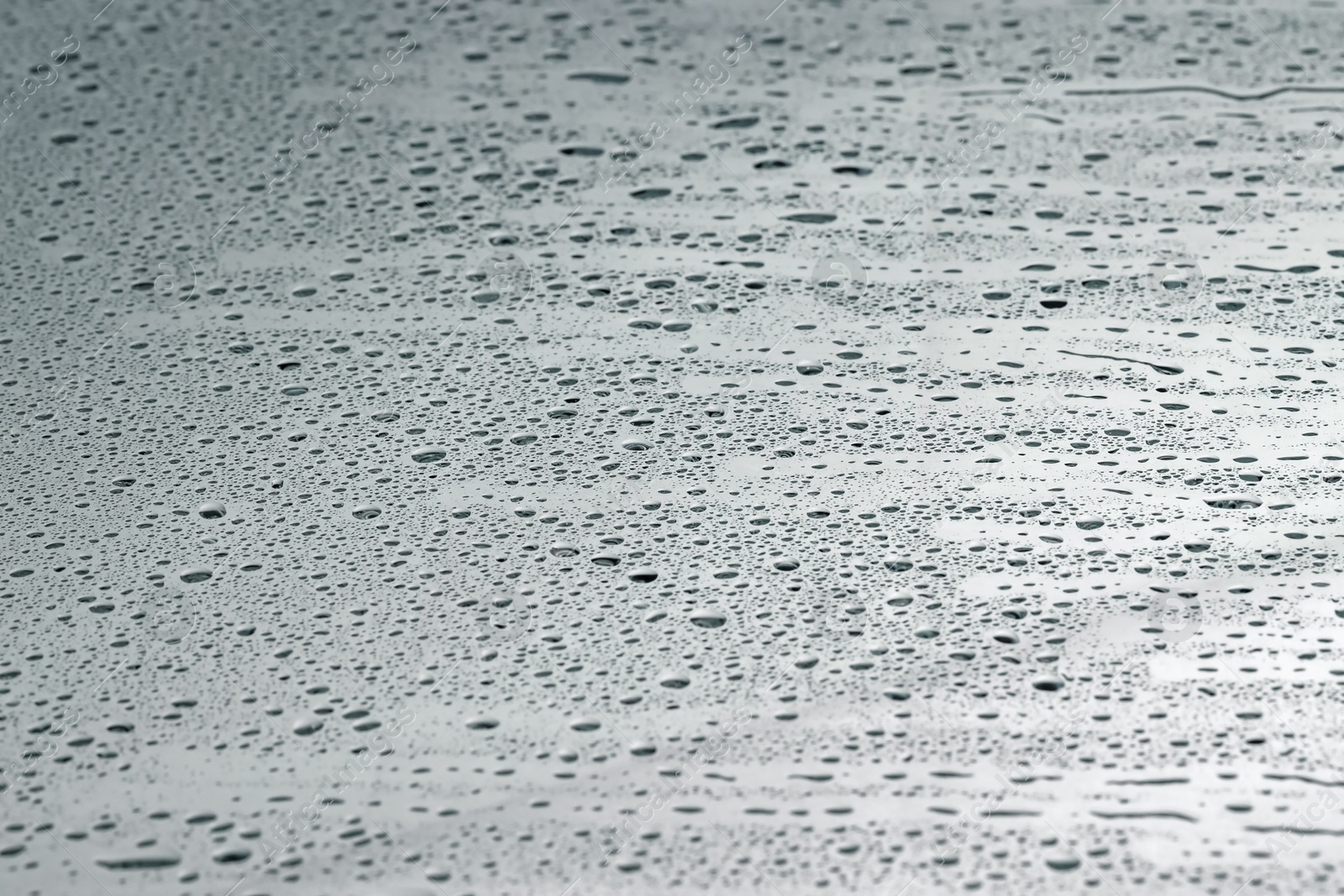 Photo of Water drops on grey glass surface, closeup