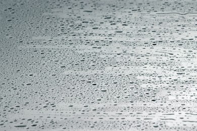 Photo of Water drops on grey glass surface, closeup