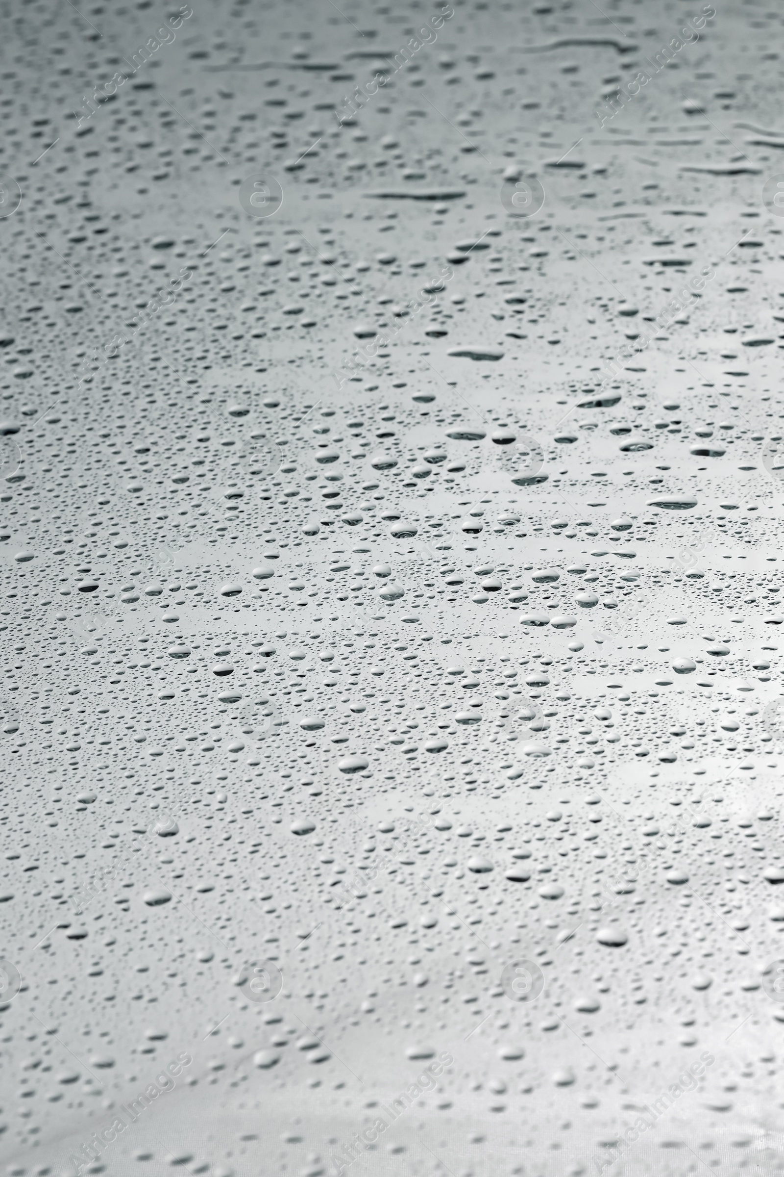 Photo of Water drops on grey glass surface, closeup