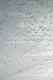 Water drops on grey glass surface, closeup