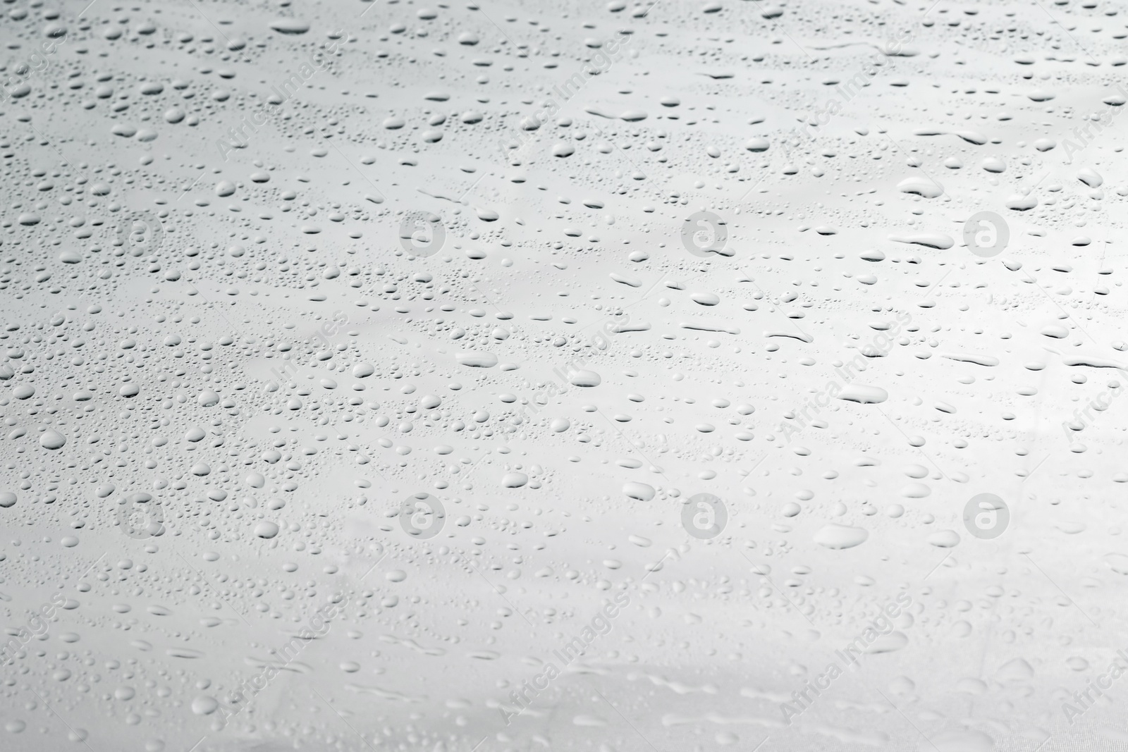 Photo of Water drops on light glass surface, closeup