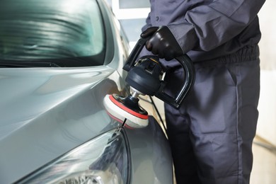 Photo of Man polishing car with orbital polisher indoors, closeup