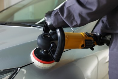 Photo of Man polishing car with orbital polisher indoors, closeup