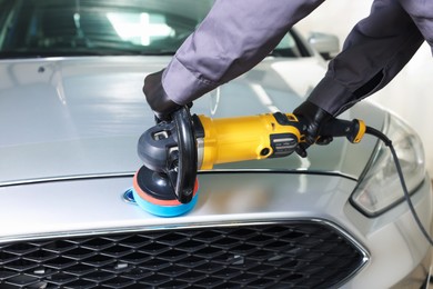 Photo of Man polishing car with orbital polisher indoors, closeup