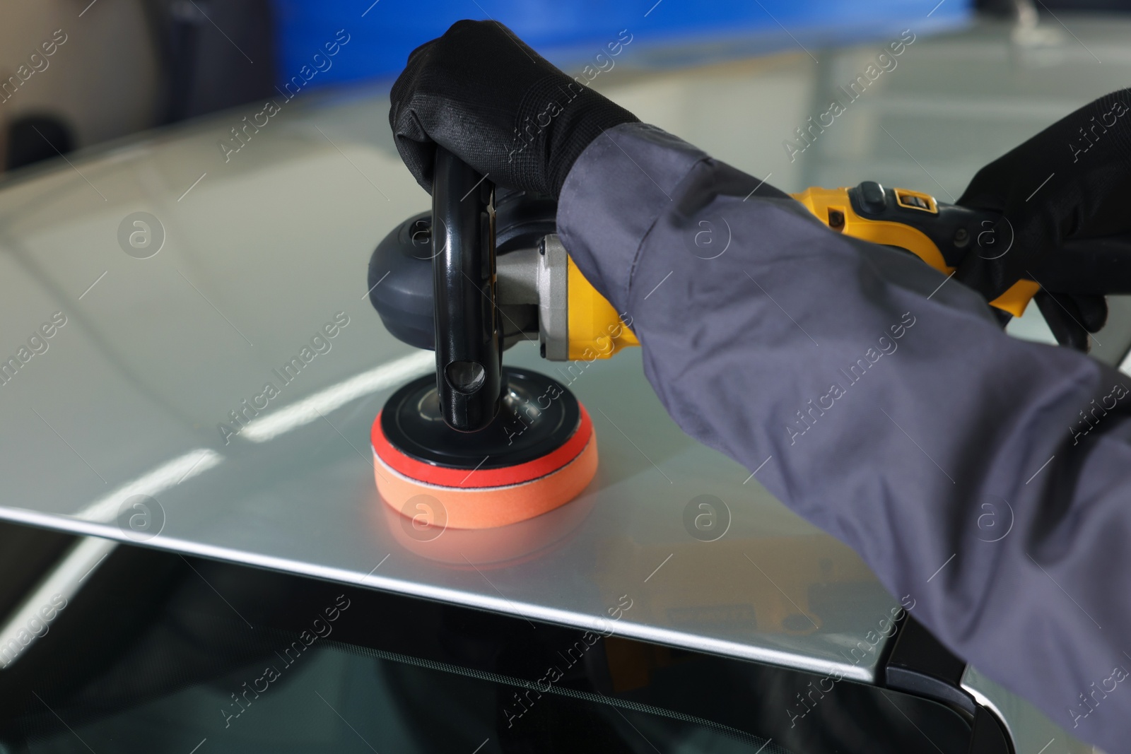 Photo of Man polishing car with orbital polisher indoors, closeup