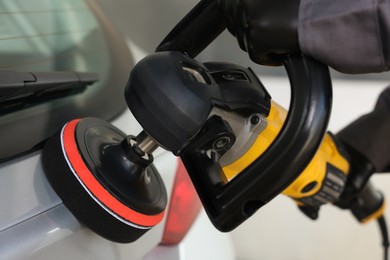 Photo of Man polishing car with orbital polisher indoors, closeup