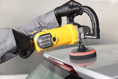 Photo of Man polishing car with orbital polisher indoors, closeup