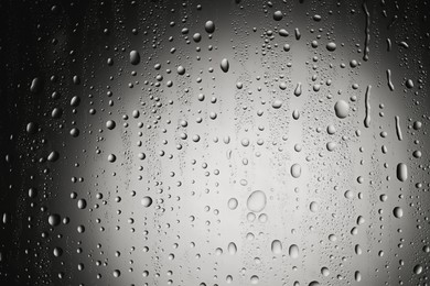 Photo of Water drops on dark grey glass surface, top view