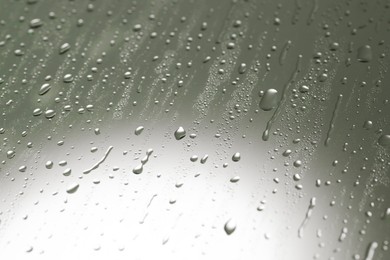 Photo of Water drops on grey glass surface, closeup