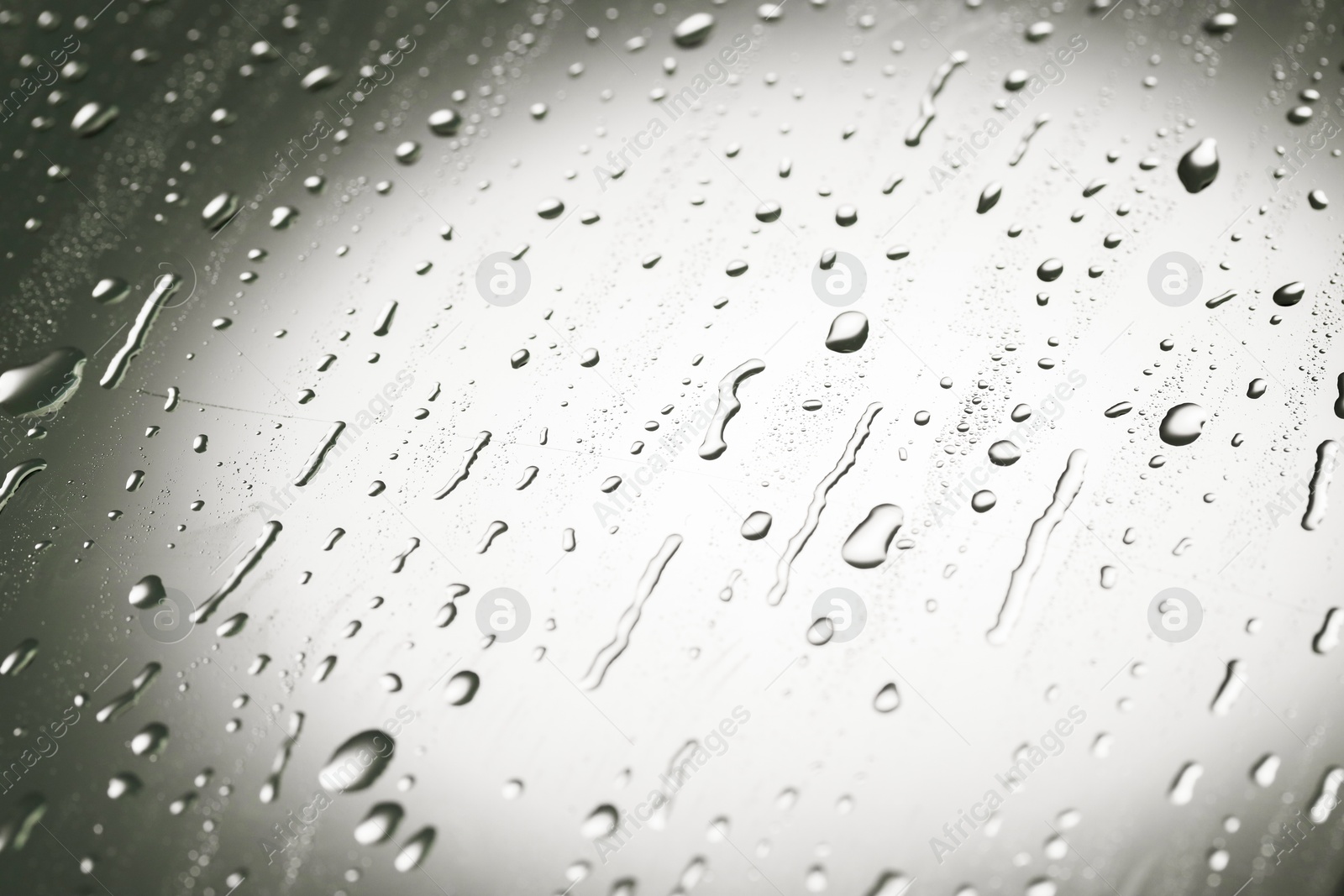 Photo of Water drops on grey glass surface, closeup