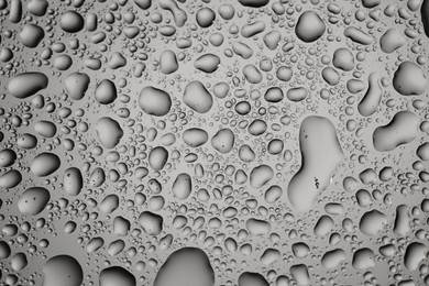 Photo of Water drops on grey glass surface, top view