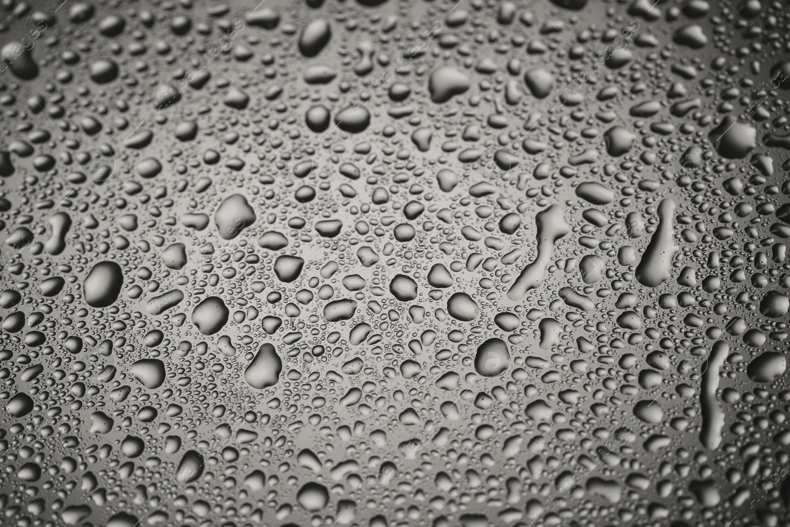 Photo of Water drops on grey glass surface, closeup