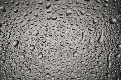 Water drops on grey glass surface, closeup