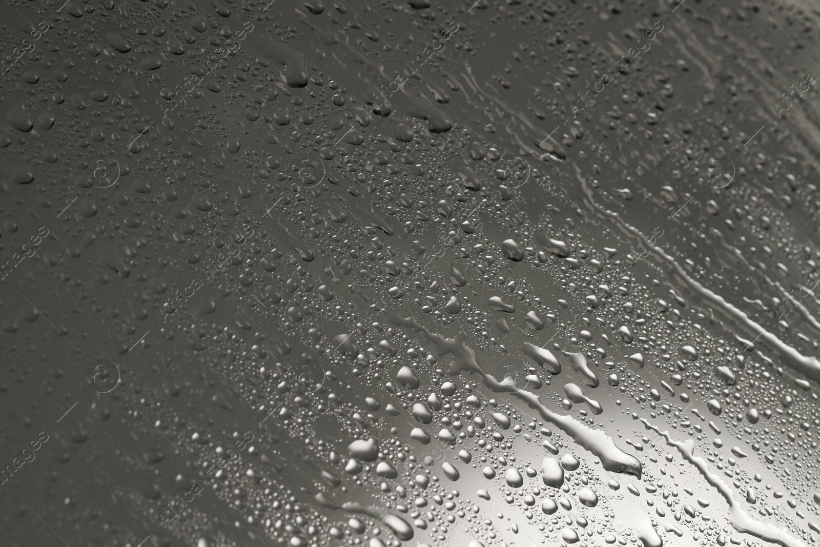 Photo of Water drops on grey glass surface, closeup