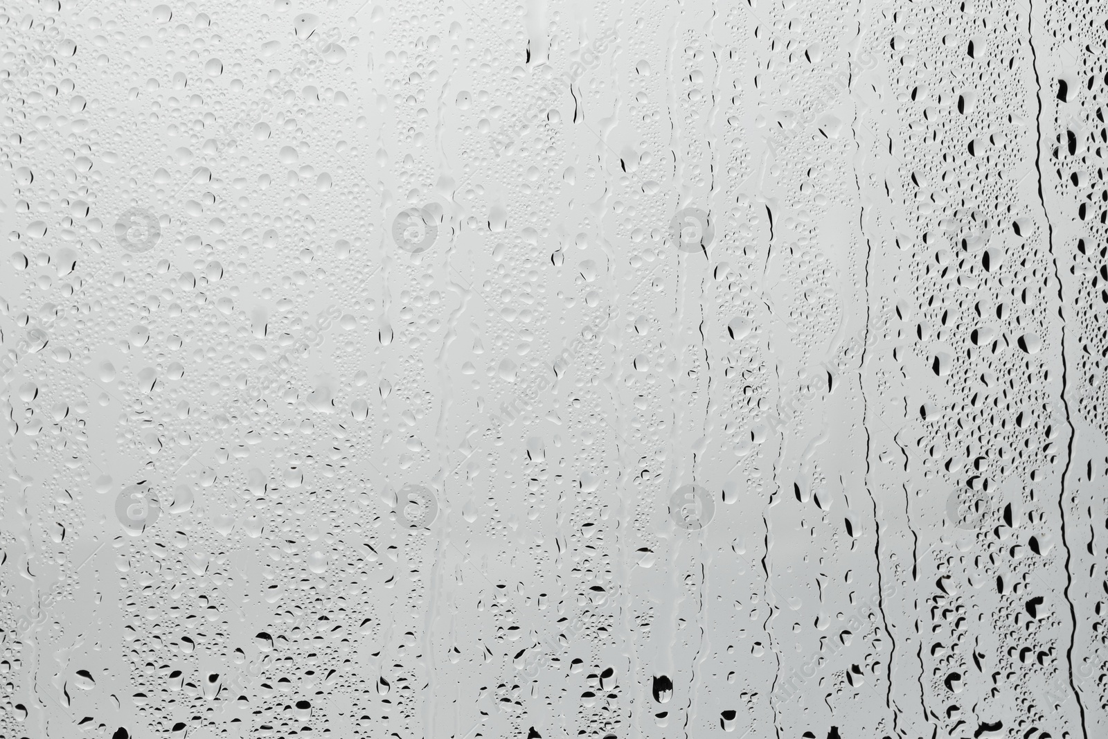 Photo of Water drops on light grey glass surface, top view