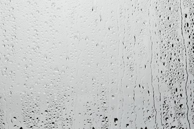 Photo of Water drops on light grey glass surface, top view