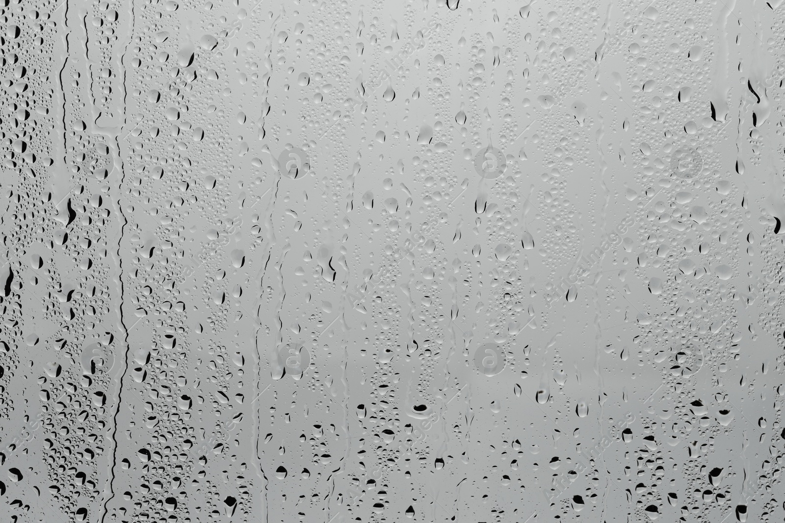 Photo of Water drops on light grey glass surface, top view