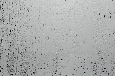 Photo of Water drops on light grey glass surface, top view