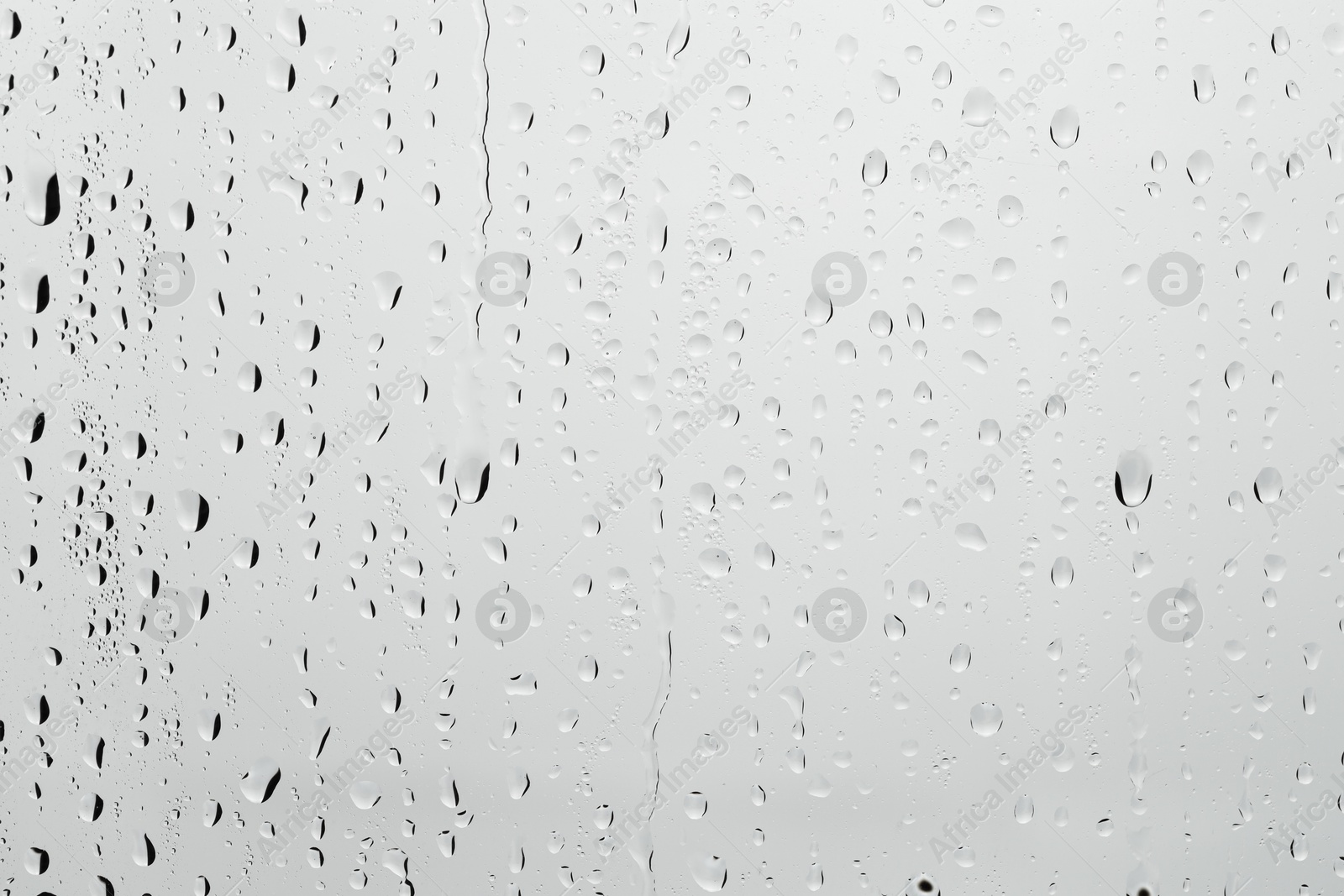 Photo of Water drops on light grey glass surface, closeup