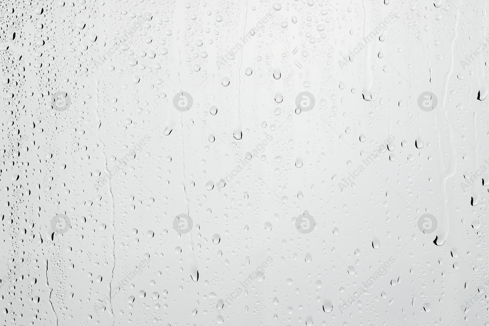 Photo of Water drops on light grey glass surface, closeup