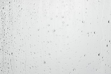 Water drops on light grey glass surface, closeup