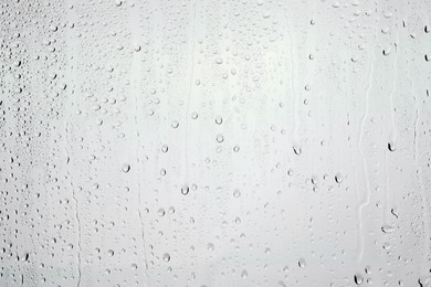 Photo of Water drops on light grey glass surface, top view