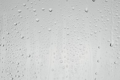 Water drops on light grey glass surface, top view