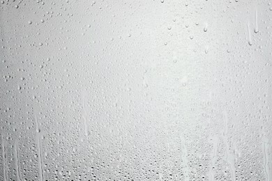 Photo of Water drops on light grey glass surface, top view